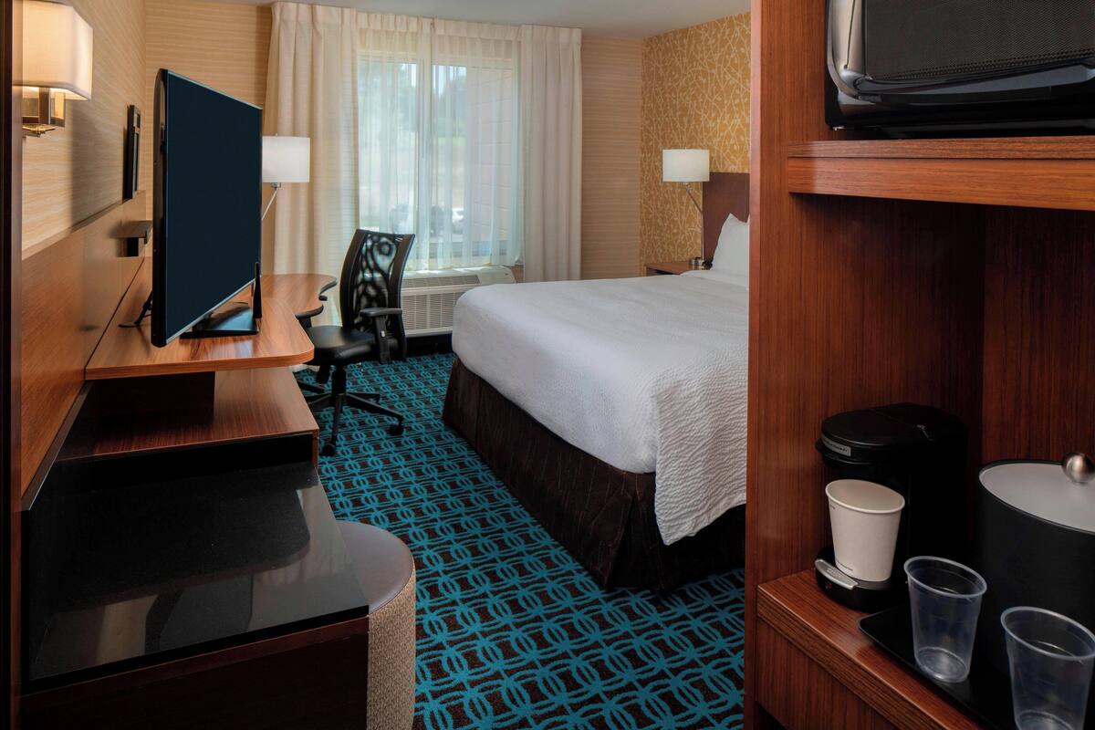 Une chambre d’hôtel équipée d’un lit, d’un bureau, d’une télévision et d’une machine à café.