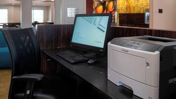 Een receptiebalie van een hotel met een computer, een printer en een zithoek.
