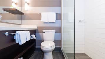 A modern bathroom with a striped wall design, a glass shower enclosure, and a dark wooden vanity.