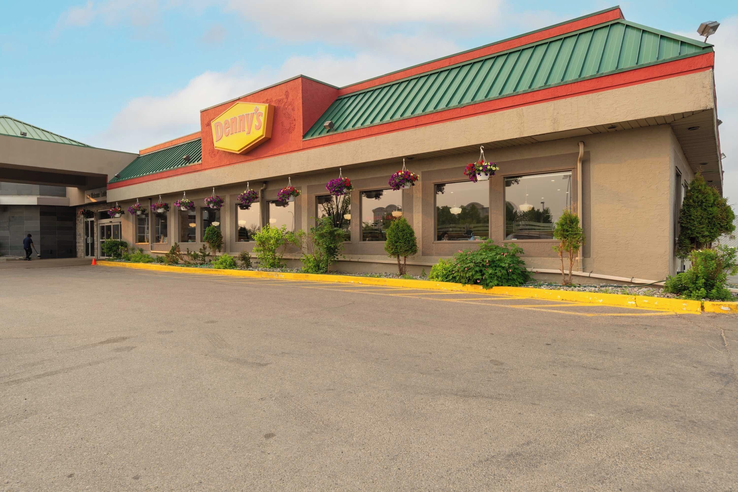 A building with a green roof and a yellow sign that reads "Denny's."