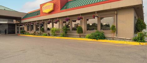A building with a green roof and a yellow sign that reads "Denny's."