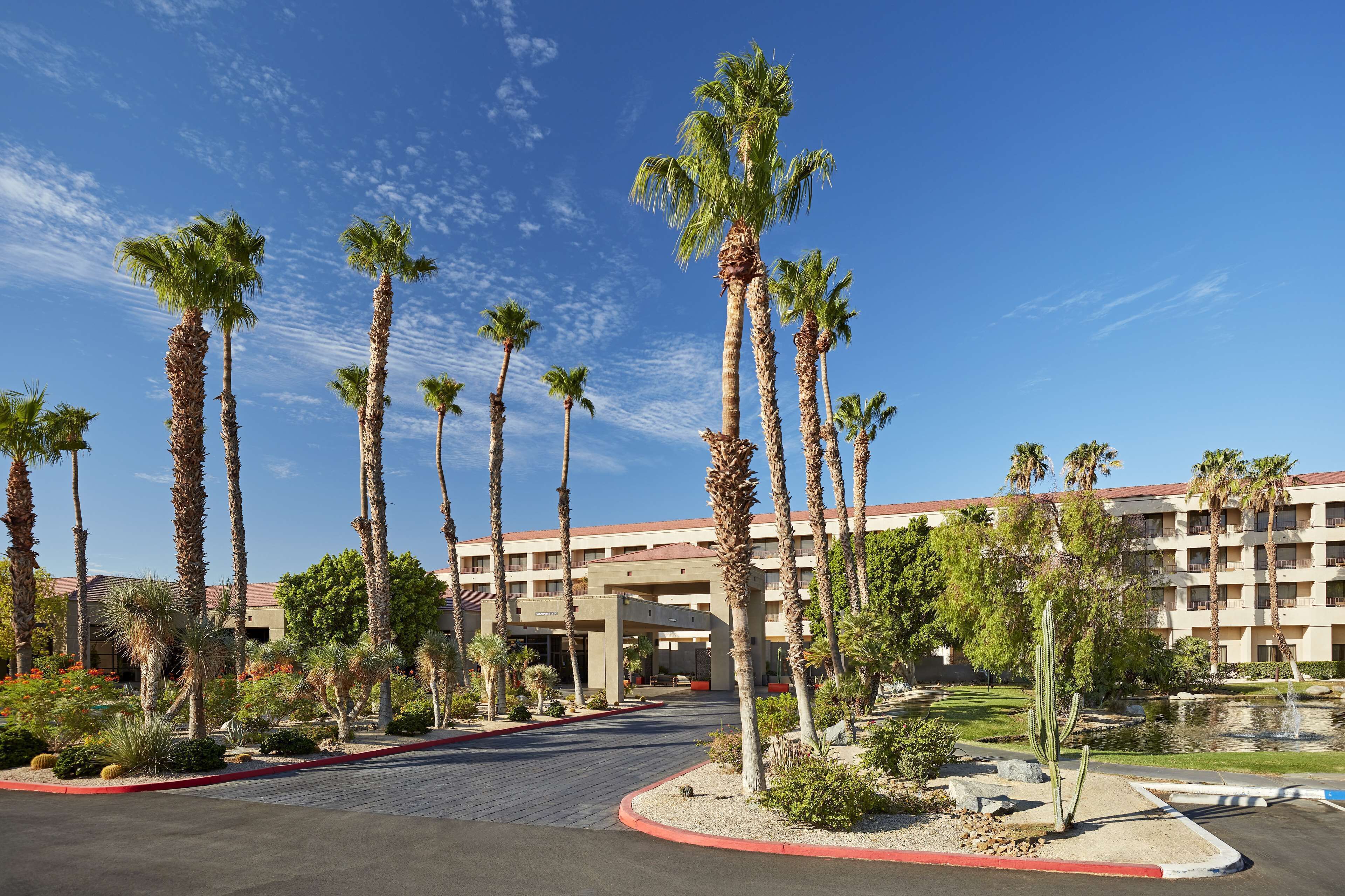 A hotel with a central courtyard, palm trees, and a pool.