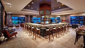 A modern bar area with a central island, bar stools, and seating arrangements. - DoubleTree by Hilton Hotel Golf Resort Palm Springs (Cathedral City)