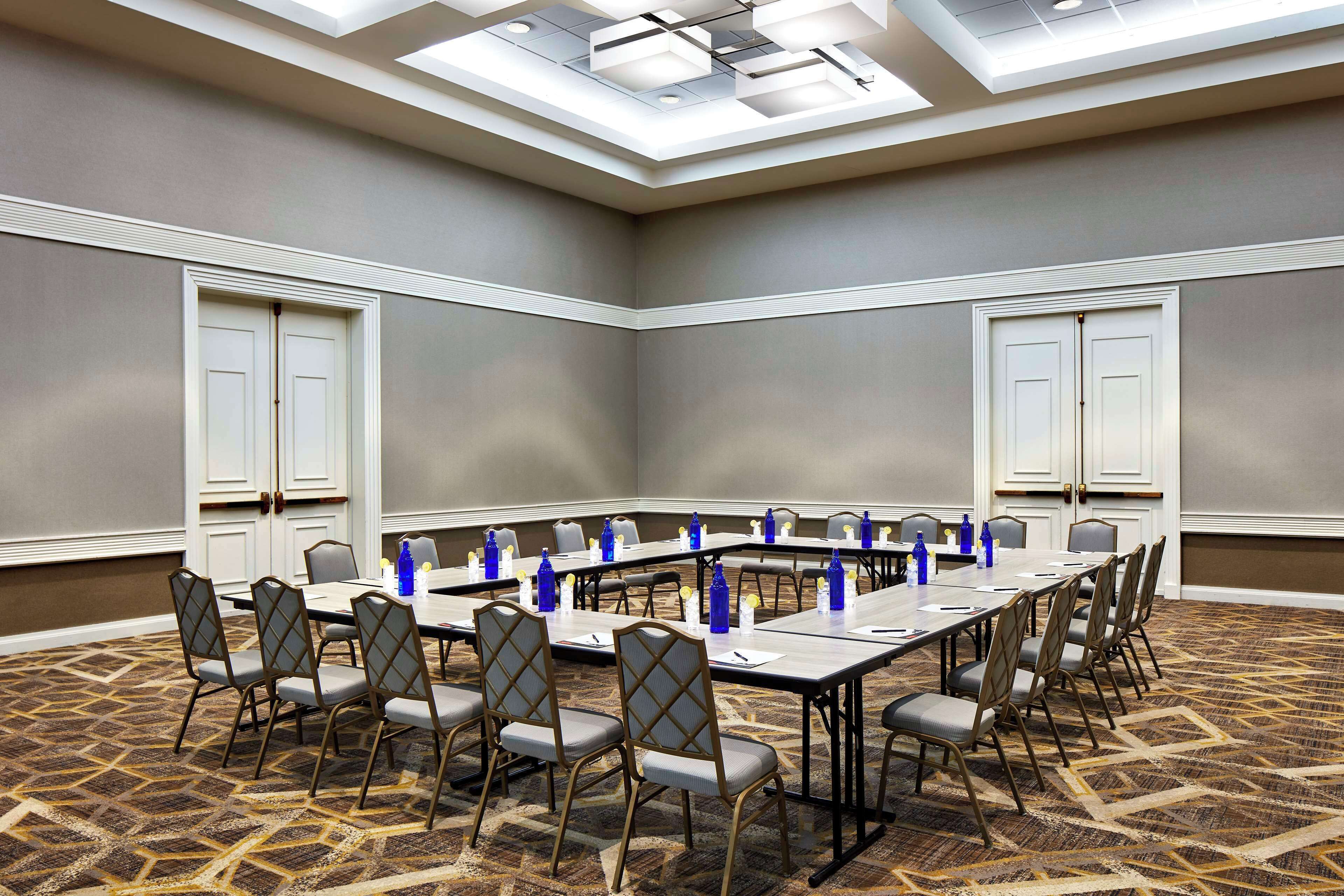 A conference room with a long table, chairs, and a patterned carpet.