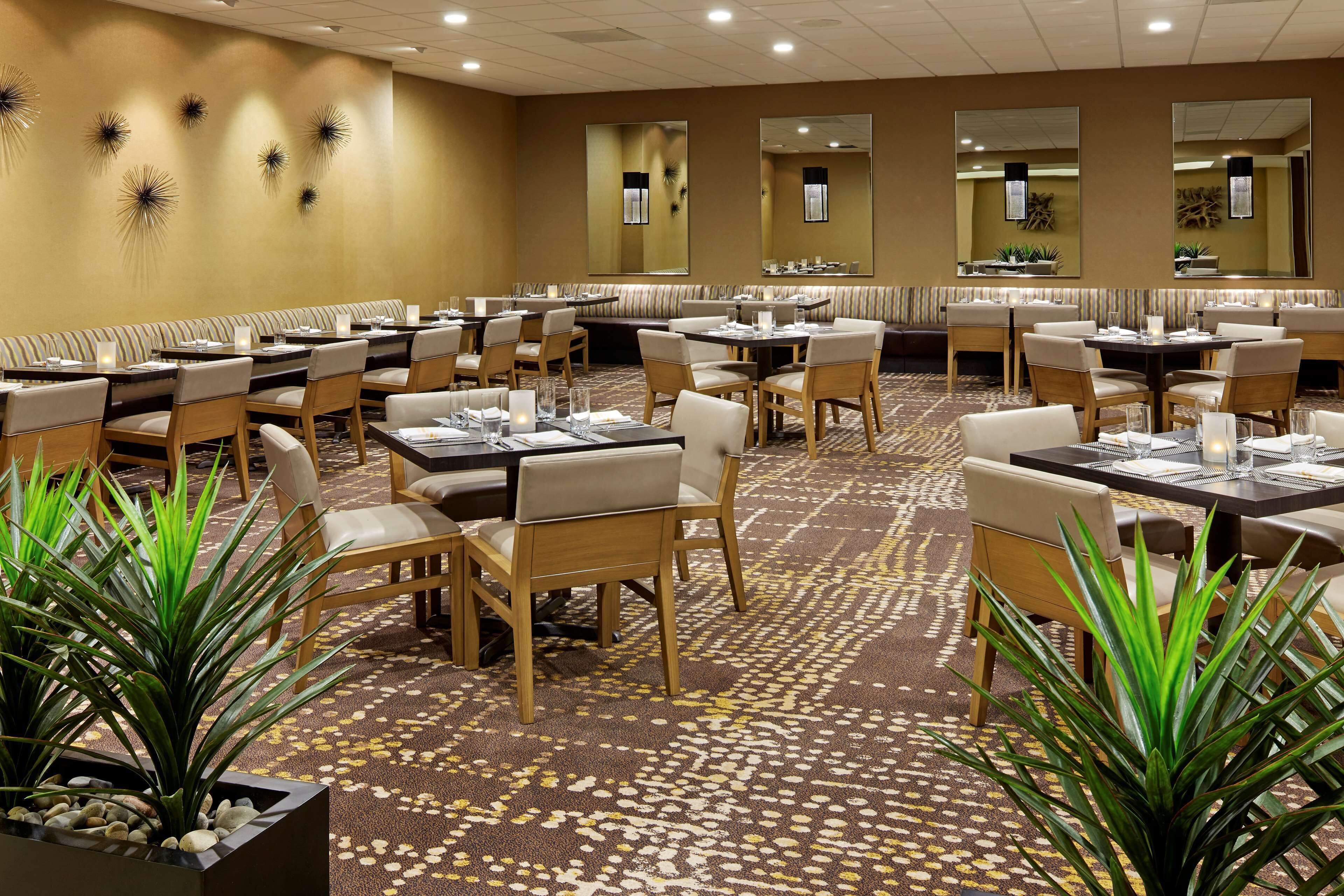 A hotel dining area with multiple tables and booths, arranged in a spacious layout.