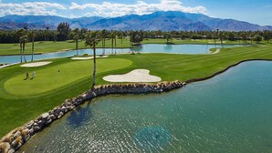 A golf course with a pond, mountains in the background, and a clear sky. - DoubleTree by Hilton Hotel Golf Resort Palm Springs (Cathedral City)