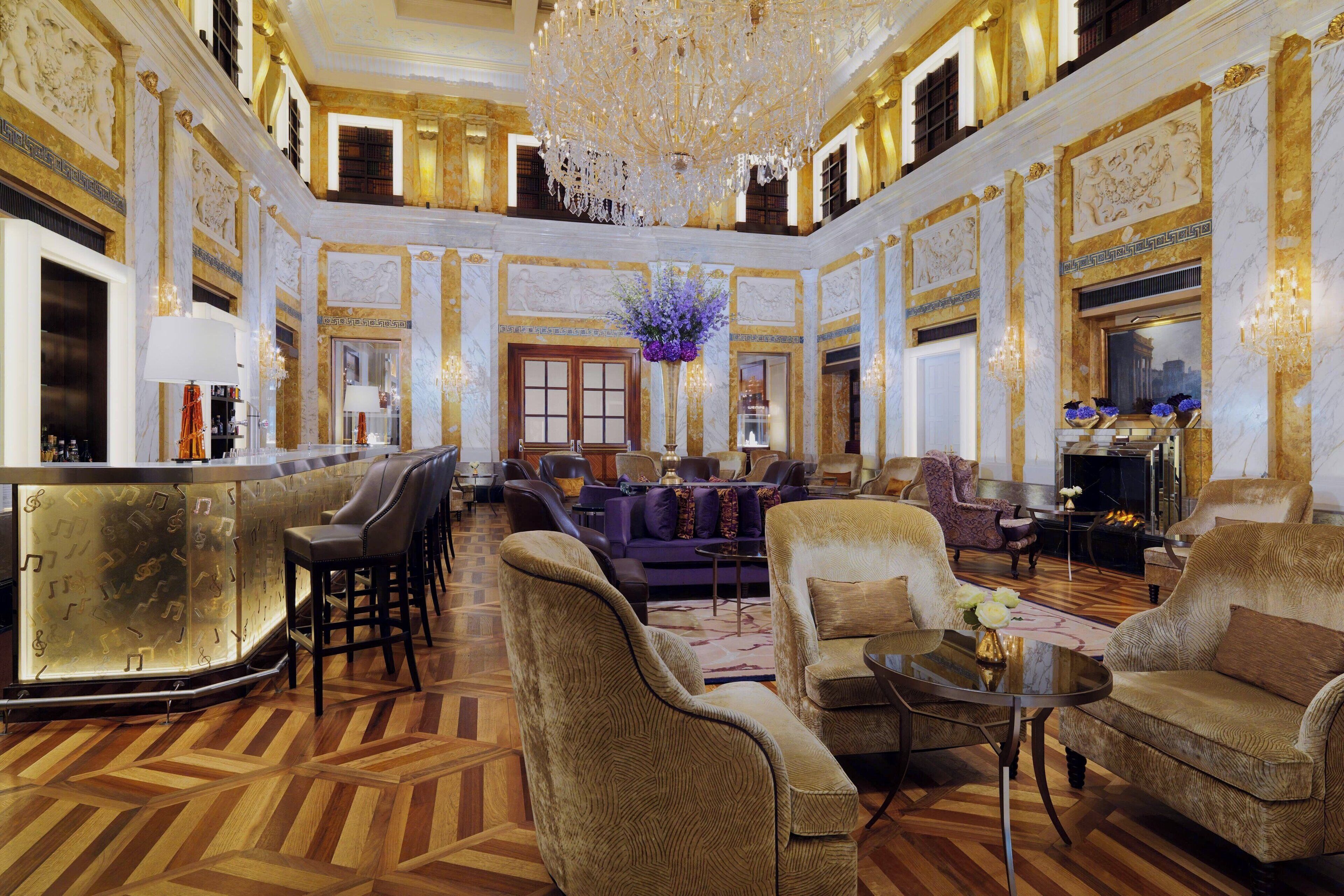 A luxurious lobby with a grand chandelier, plush seating, and ornate decor.