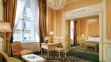 Una habitación de hotel con un ventanal grande, un candelabro, un escritorio y una cama.