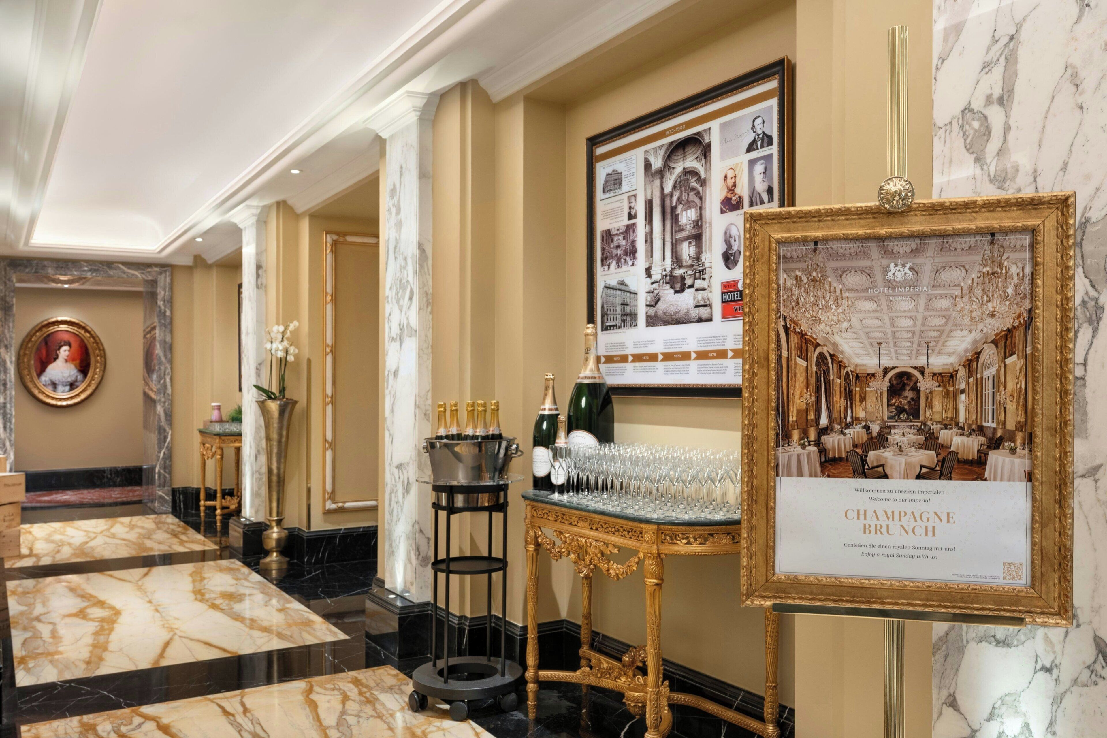 A grand hotel lobby with marble floors, a chandelier, and a champagne brunch sign.