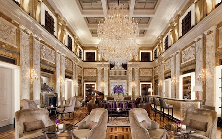 A grand lobby with marble columns, a large chandelier, and a bar area.