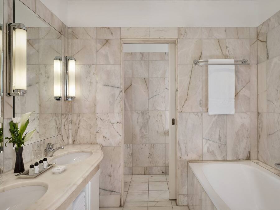 A modern bathroom with two sinks, a bathtub, and a shower.