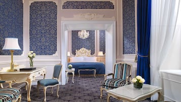 A luxurious bedroom with a large bed, ornate furniture, and a patterned carpet.