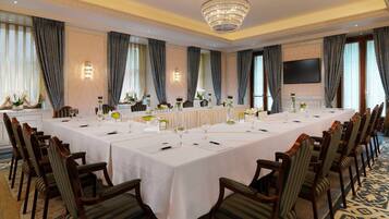 A large conference room with a long table, chairs, and a chandelier.