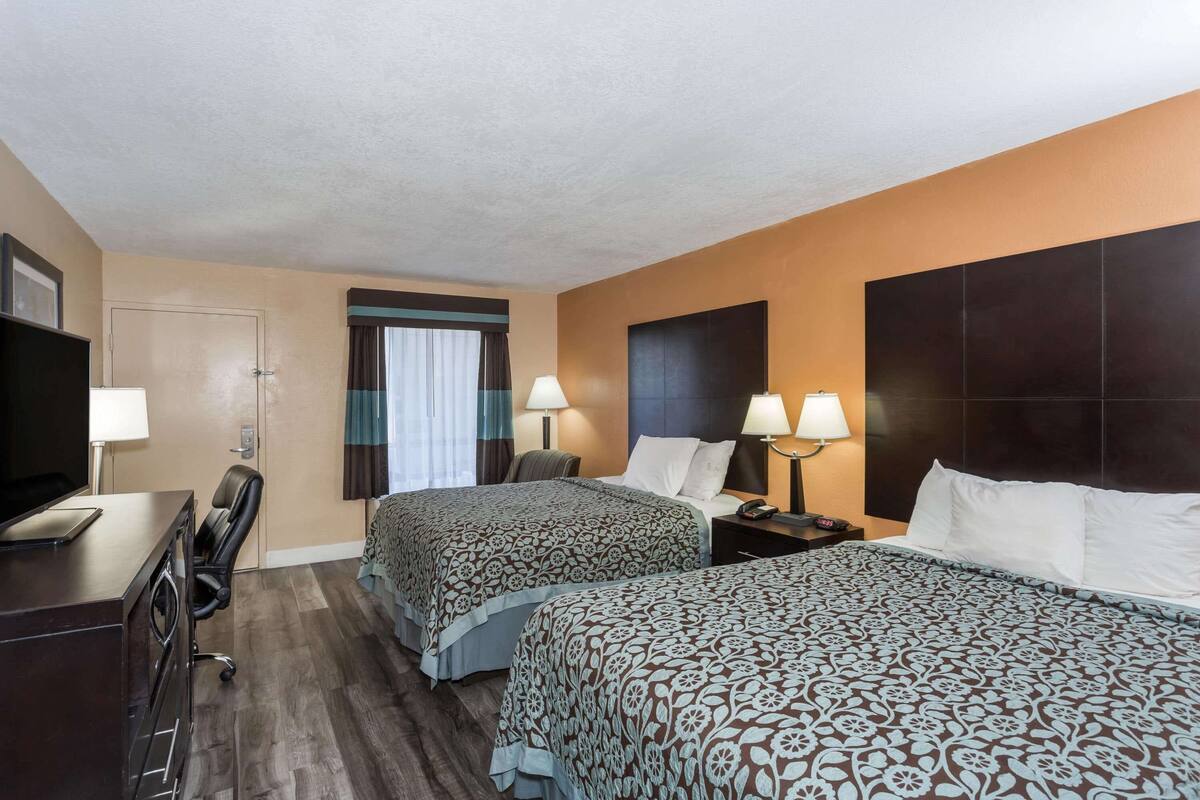 Une chambre d’hôtel avec deux lits, un bureau avec un ordinateur et une télévision.