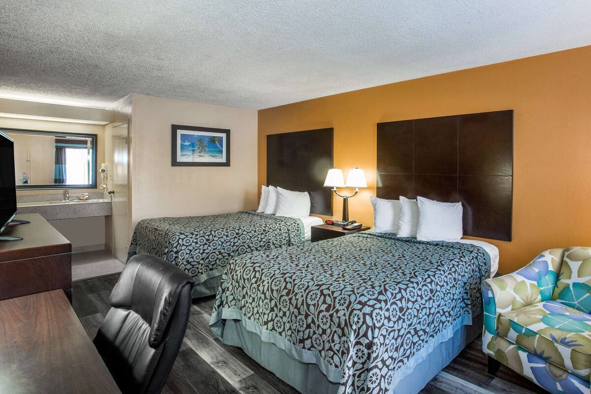 Une chambre d’hôtel avec deux lits, un bureau, une chaise et un téléviseur.