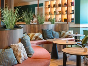 A modern lounge area with seating, tables, and decorative plants. - ibis Styles Lyon Sud Vienne (Chasse-sur-Rhone)