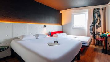 Et hotelværelse med en stor seng, en mindre seng, et skrivebord med stol, et vindue og udsigt til det fri.