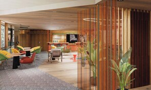 A modern hotel lobby with colorful chairs, a bar area, and a decorative curtain. - ibis Styles Lyon Sud Vienne (Chasse-sur-Rhone)