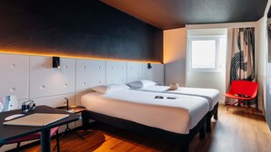 A modern hotel room with a large bed, a desk, a chair, and a window with curtains. - ibis Styles Lyon Sud Vienne (Chasse-sur-Rhone)