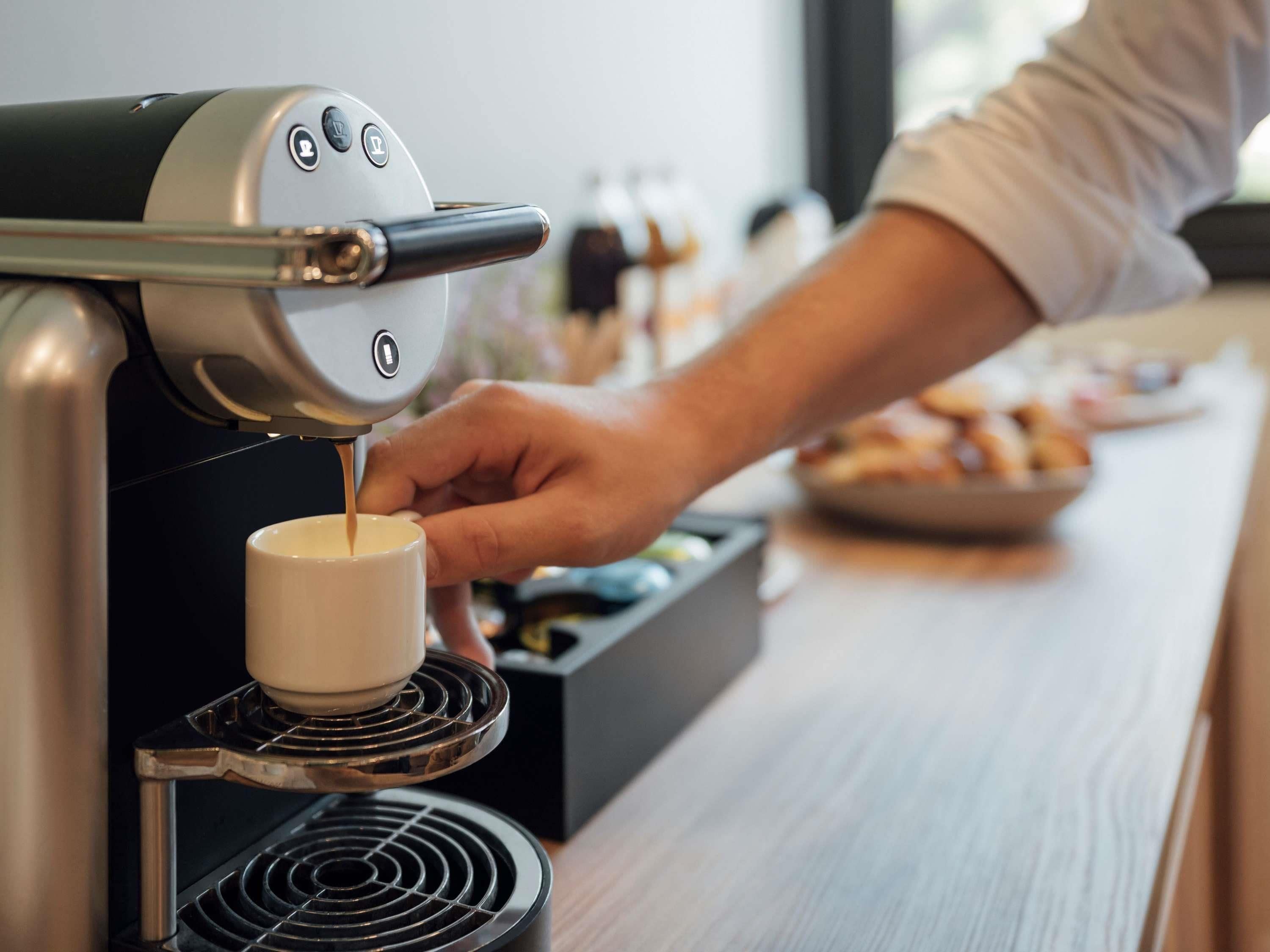Une personne utilise une machine à café pour verser du café dans une tasse.