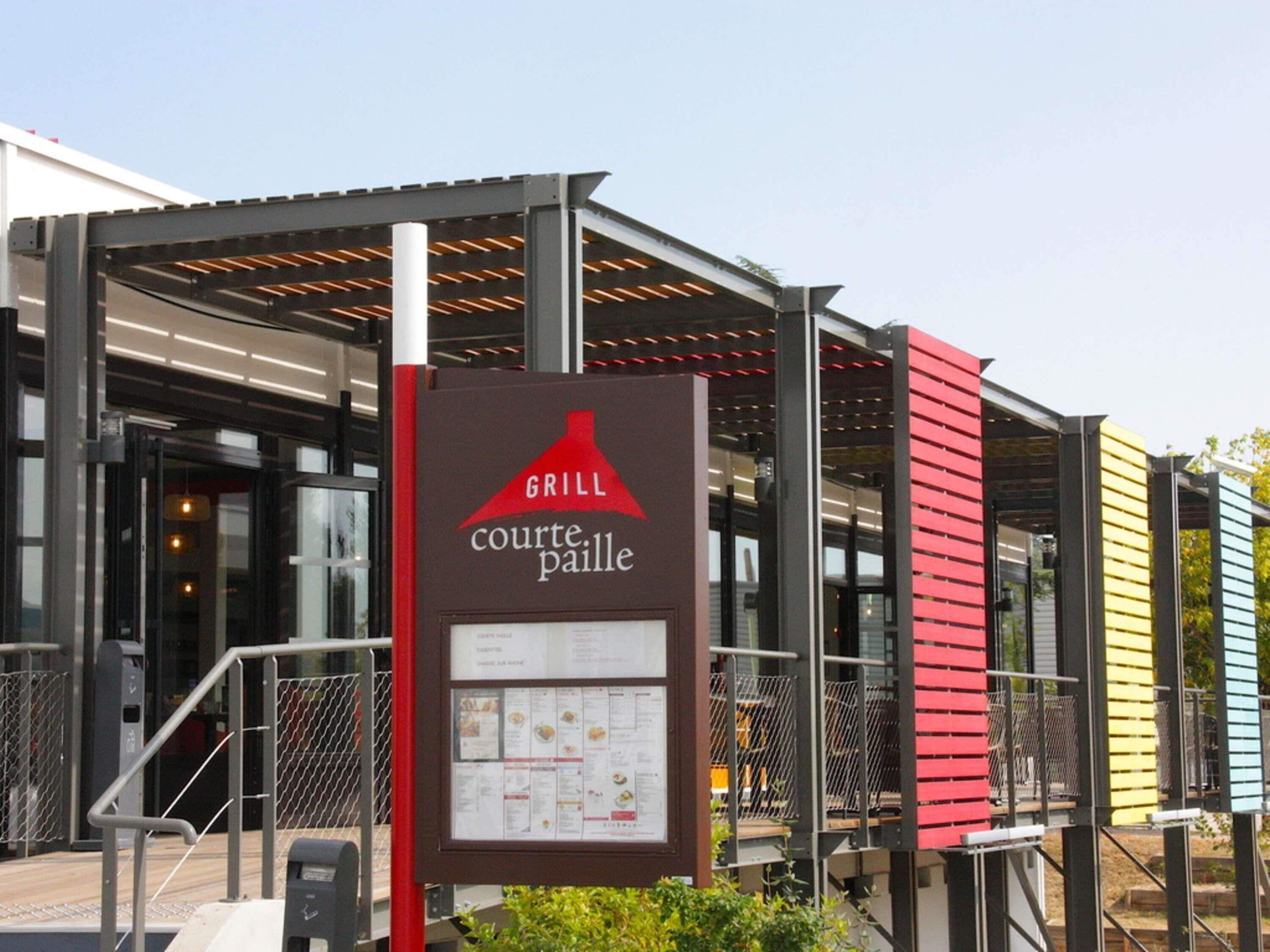 Letrero de restaurante con símbolo de parrilla y cartel de menú.