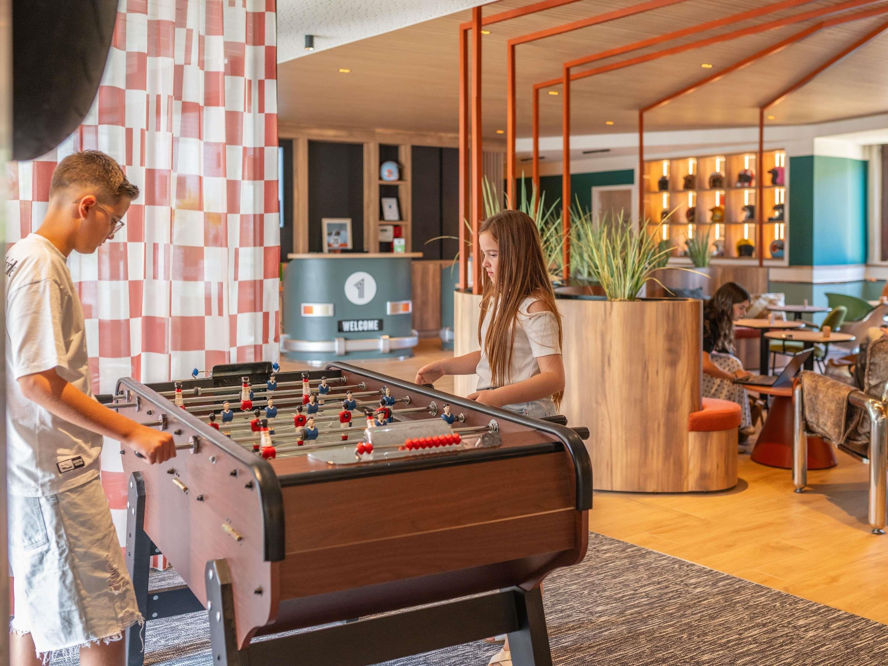 A foosball table in a modern lobby with a checkered wall and a reception desk.