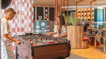 A foosball table in a modern lobby with a checkered wall and a reception desk.