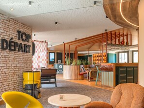 A modern lounge area with a brick wall, a reception desk, and a bar area. - ibis Styles Lyon Sud Vienne (Chasse-sur-Rhone)