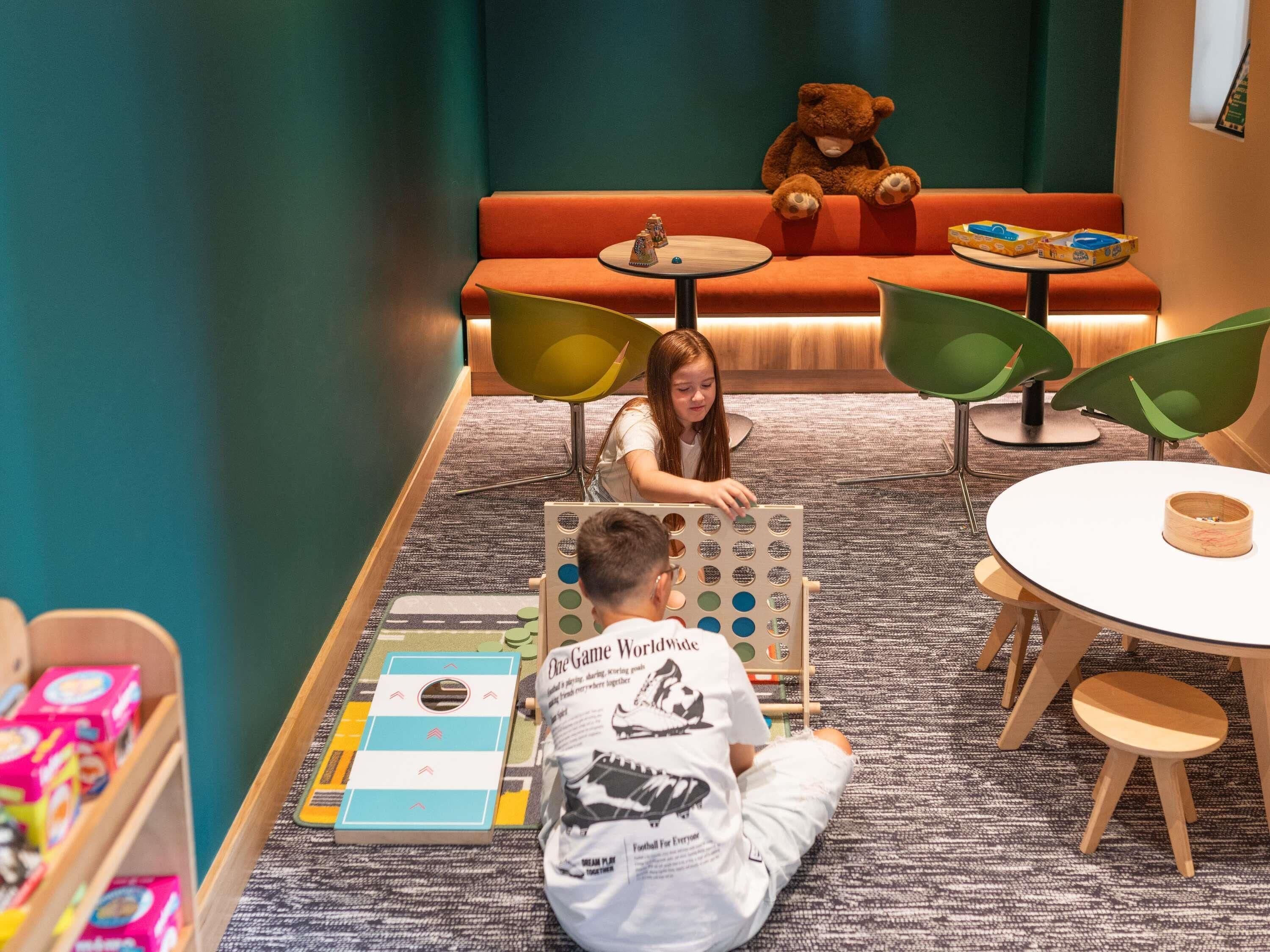 A children's play area with a football field mat, a teddy bear, and a table with a bowl.
