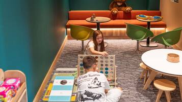 A children's play area with a football field mat, a teddy bear, and a table with a bowl.
