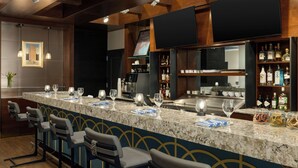 A bar area with a marble countertop, bar stools, and a wine glass display. - Courtyard by Marriott San Francisco Union Square (San Francisco)