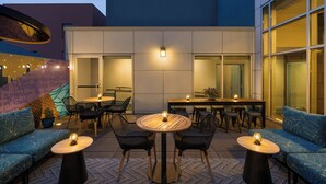 An outdoor seating area with round tables and chairs, a sofa, and a small table with a candle. - Courtyard by Marriott San Francisco Union Square (San Francisco)