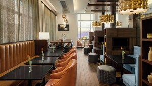 A modern hotel lobby with leather seating, a fireplace, and a large window offering a view. - Courtyard by Marriott San Francisco Union Square (San Francisco)