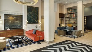 A spacious lobby with a modern chandelier, a large abstract painting, a red sofa, and a seating area with a blue sofa and armchairs. - Courtyard by Marriott San Francisco Union Square (San Francisco)
