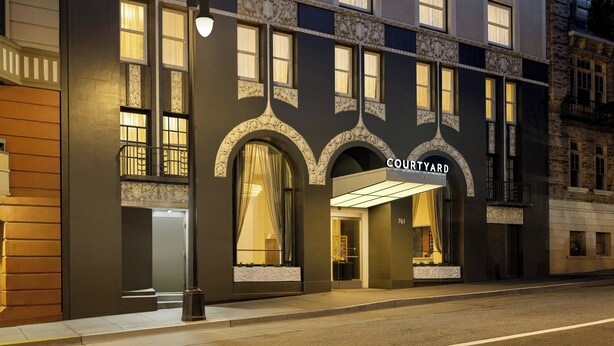 A building with a dark facade, large arched windows, and the name 'COURTYARD' prominently displayed above the entrance. - Courtyard by Marriott San Francisco Union Square (San Francisco)