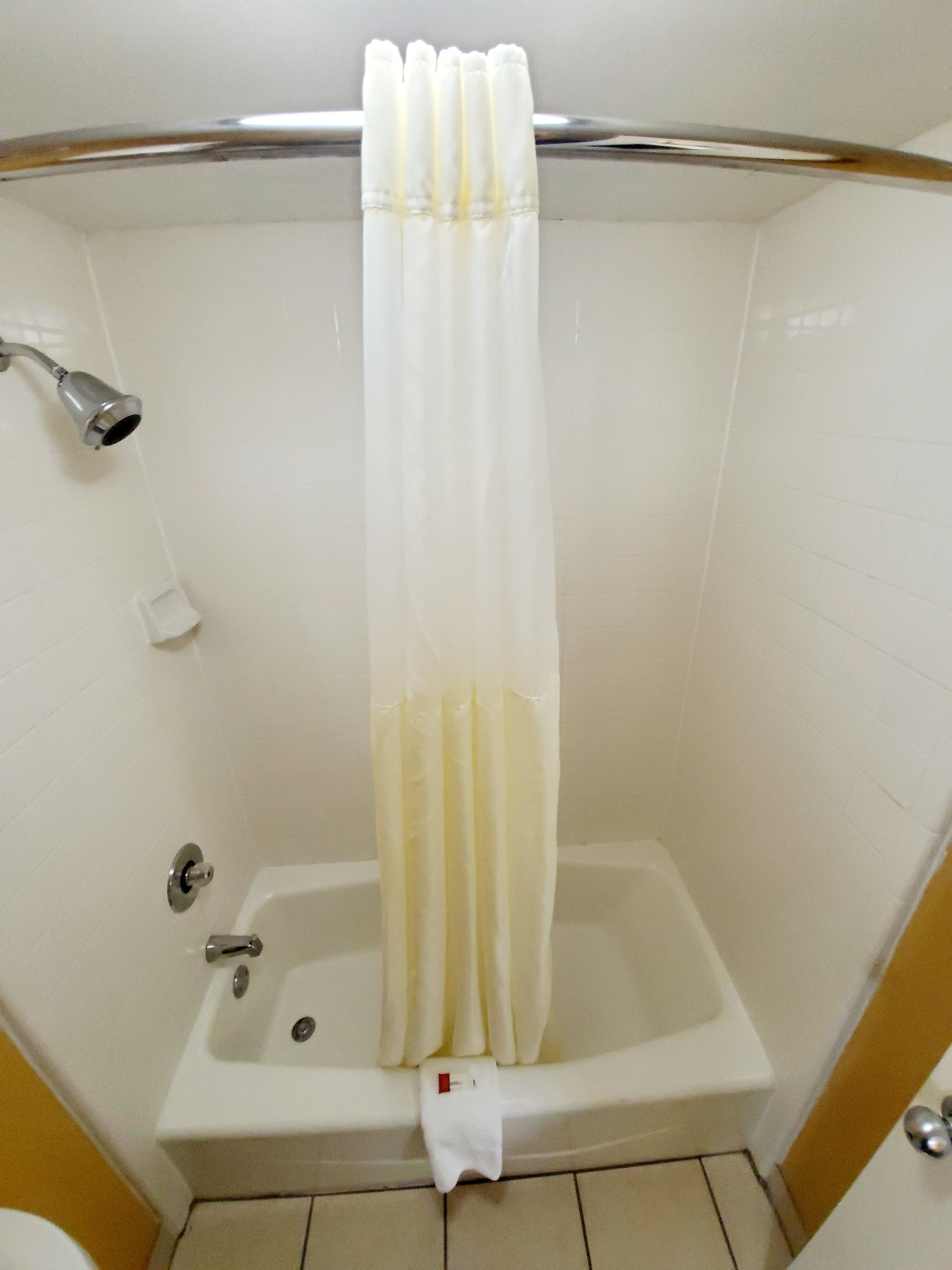 A bathroom with a bathtub, a shower curtain, and a toilet.