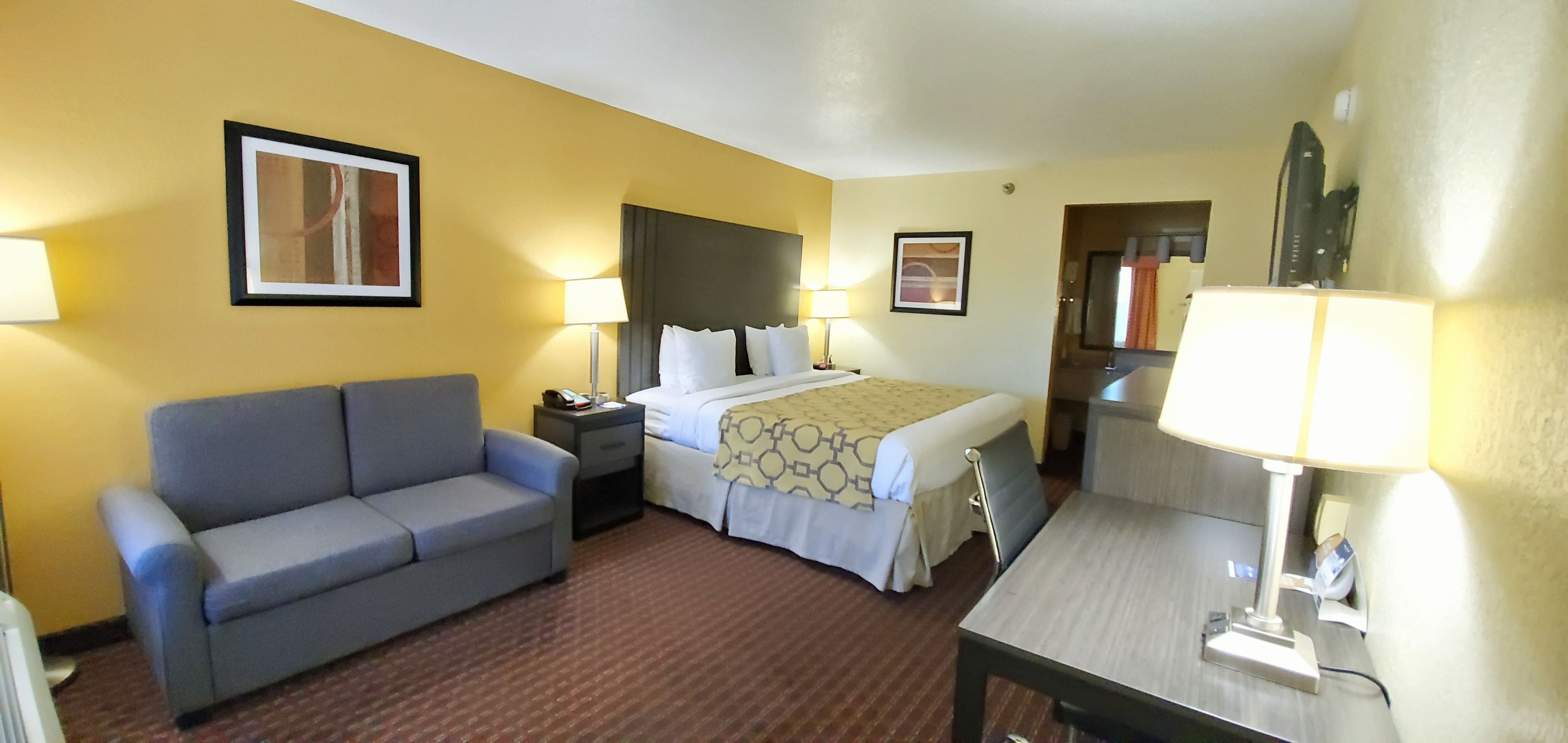 Een hotelkamer met een bed, een slaapbank, een bureau en twee lampen.