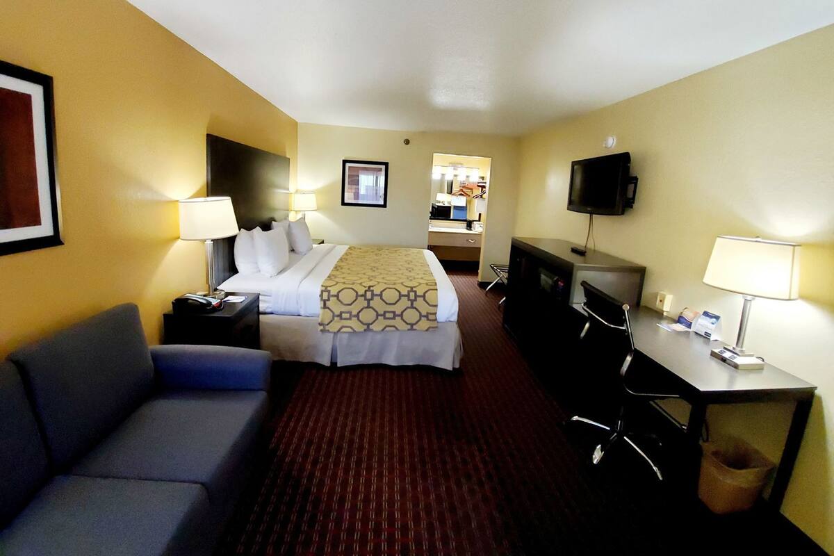 Une chambre d’hôtel comprenant un lit, un bureau, une télévision, un canapé et un miroir.