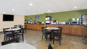 A breakfast area with tables and chairs, a coffee machine, a microwave, and a TV on the wall. - Baymont by Wyndham Goodlettsville/Nashville (Goodlettsville)