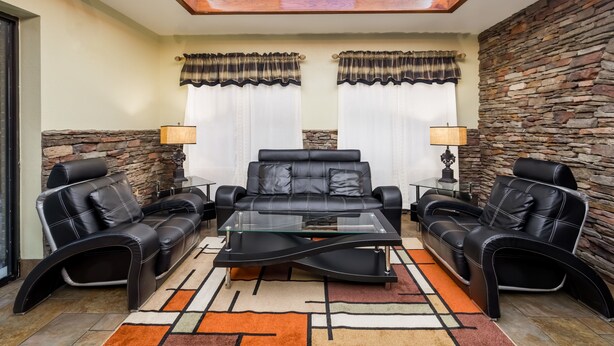 A modern living room with a glass coffee table, leather sofas, and a stone accent wall. - Baymont by Wyndham Goodlettsville/Nashville (Goodlettsville)