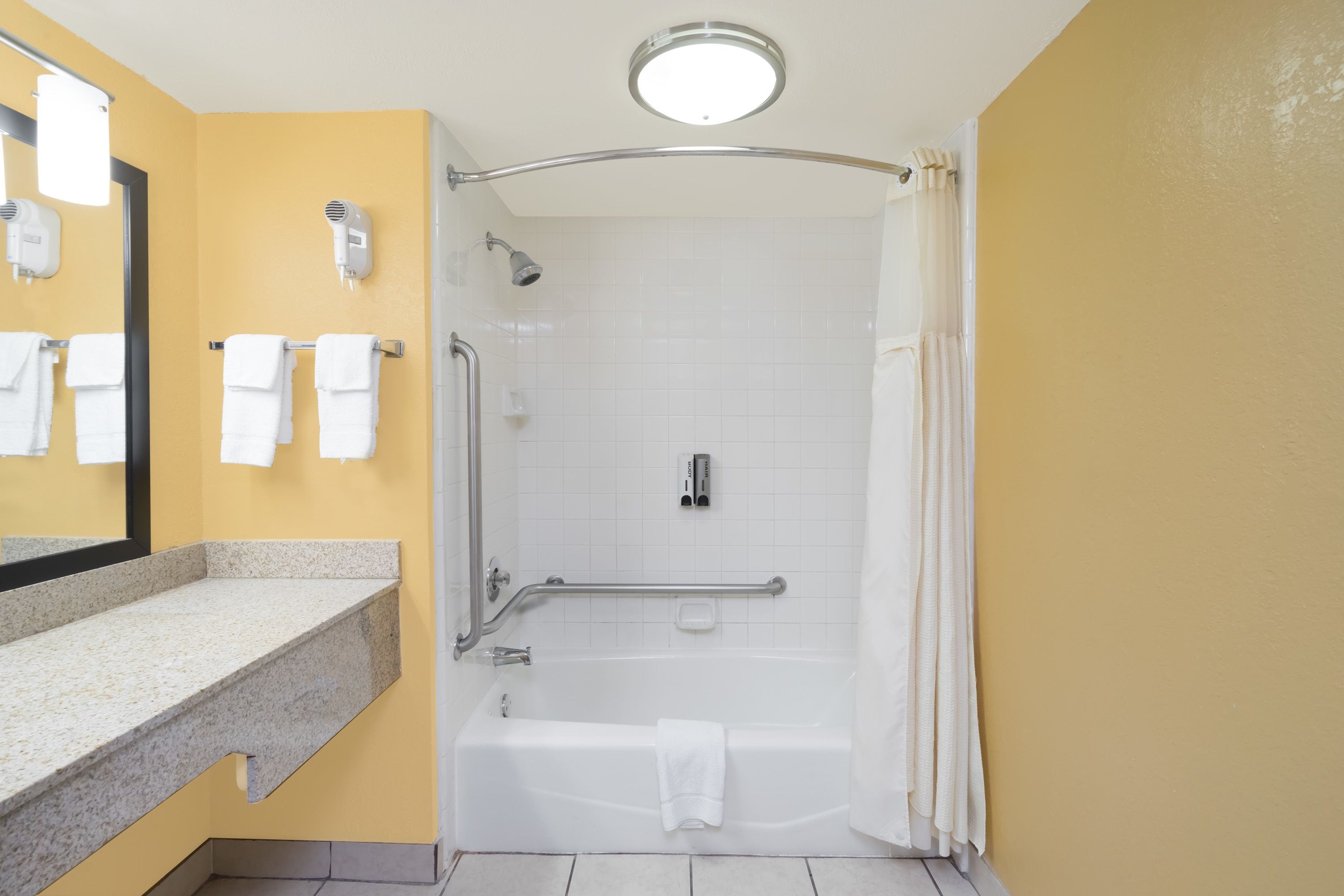 Ein Badezimmer mit Dusche, Badewanne, Waschtisch mit Spiegel und Handtuchhalter.