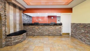 A reception area with a stone wall, a Baymont Inn & Suites sign, and a black bench. - Baymont by Wyndham Goodlettsville/Nashville (Goodlettsville)