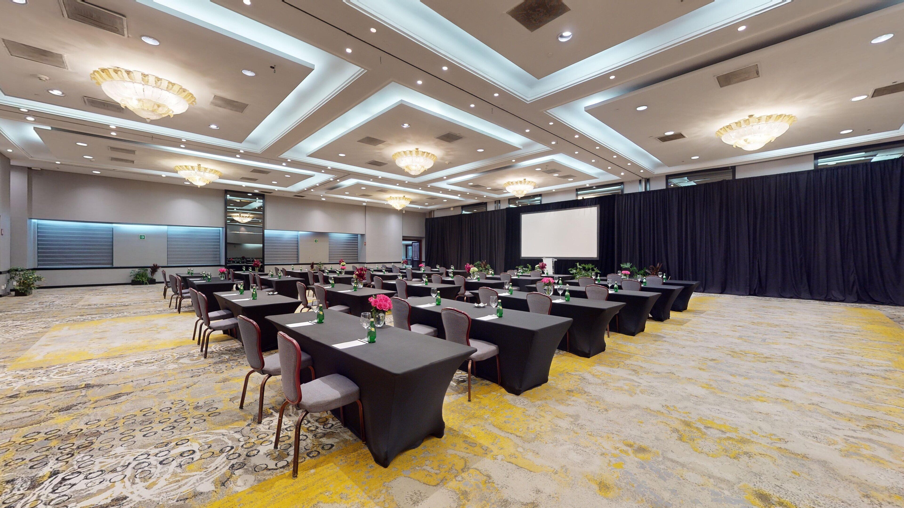 A conference room with tables, chairs, and a projector screen.