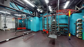 Un gimnasio con equipo de levantamiento de pesas, un espejo y un estante con mancuernas.