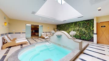 A hotel lobby with a swimming pool, lounge chairs, and a wall of greenery.