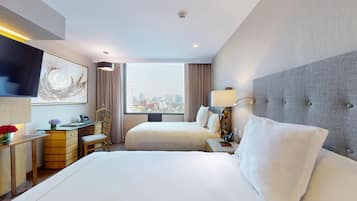 A hotel room with two beds, a desk, a chair, a TV, and a city view.