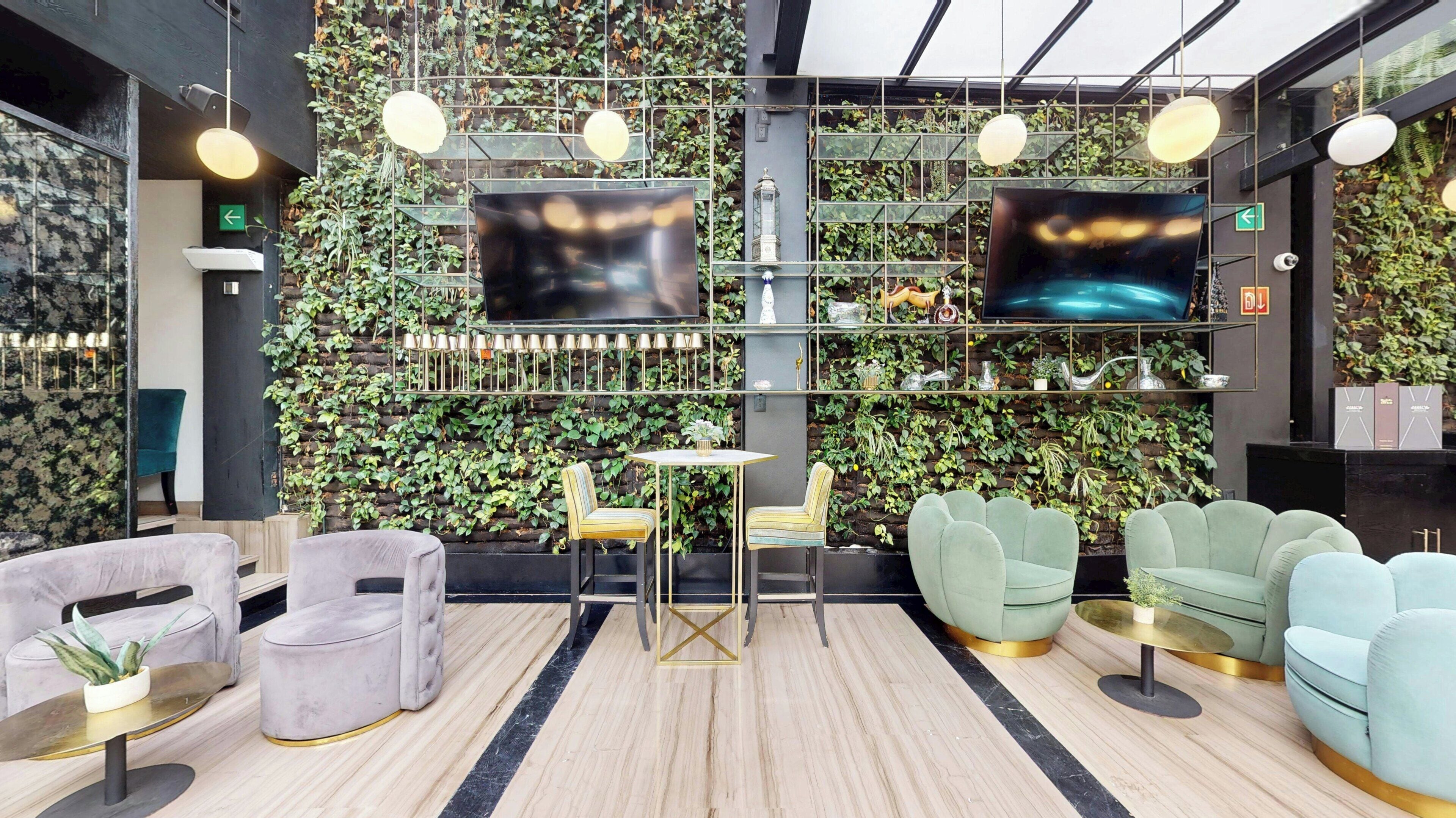 Een modern interieur met een tv aan de muur, een zithoek en een decoratieve plantenwand.