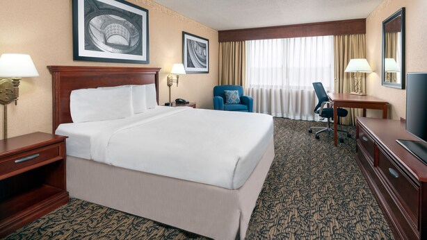 Une chambre d’hôtel avec un grand lit, un bureau, une chaise et un téléviseur.