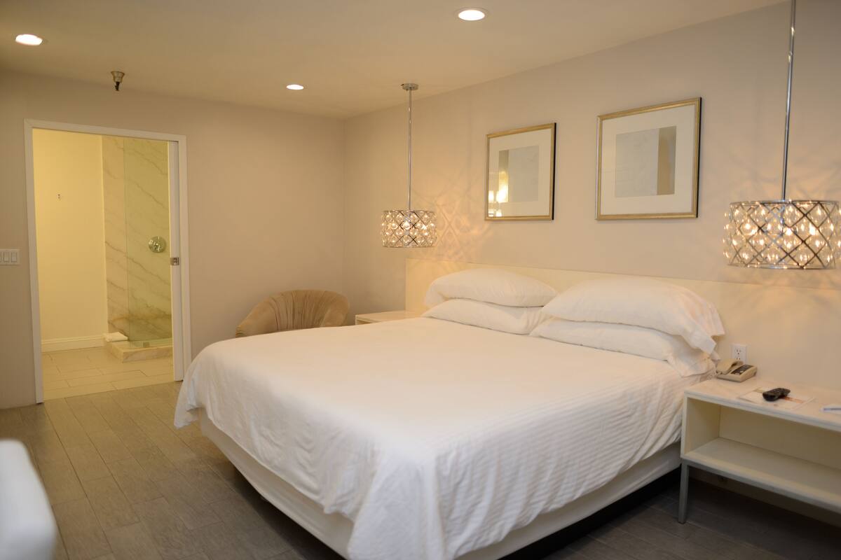 A bedroom with a large bed, bedside tables, and two wall-mounted lamps.