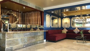A lobby with a marble reception desk, a red sofa, and a chandelier. - Hotel Le Rêve Pasadena (Pasadena)